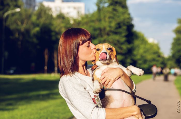 Foto de una mujer dándole un beso a su perro