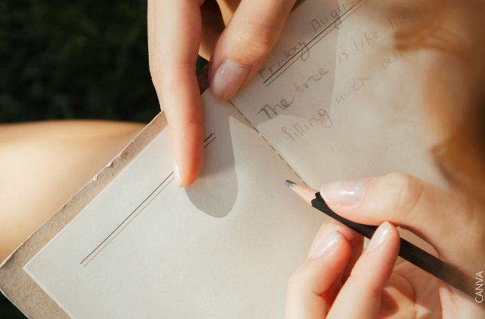 Foto de una mano con un lápiz escribiendo en un cuaderno