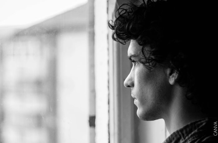 Foto a blanco y negro de un hombre viendo por una ventana