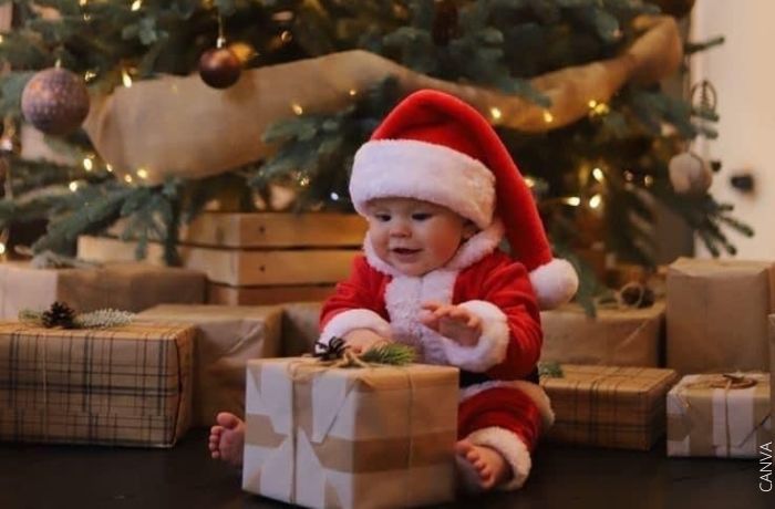 Foto de un bebé con ropa de Navidad y un regalo