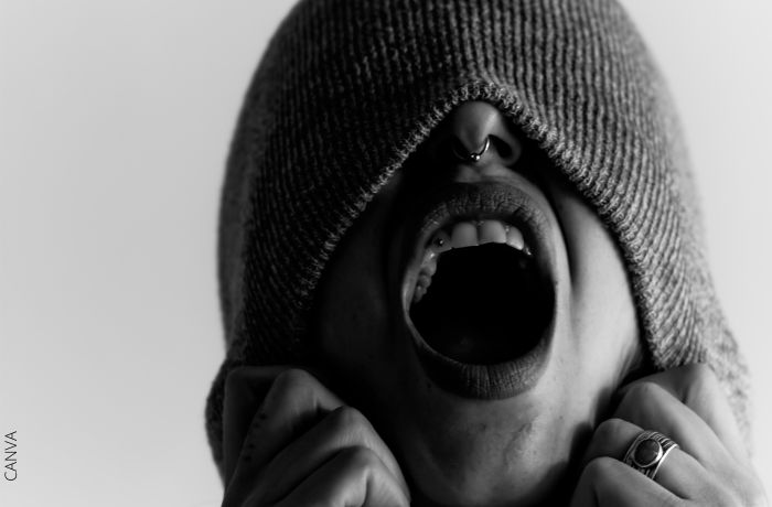 Foto a blanco y negro de una persona gritando con la mitad de la cara tapada
