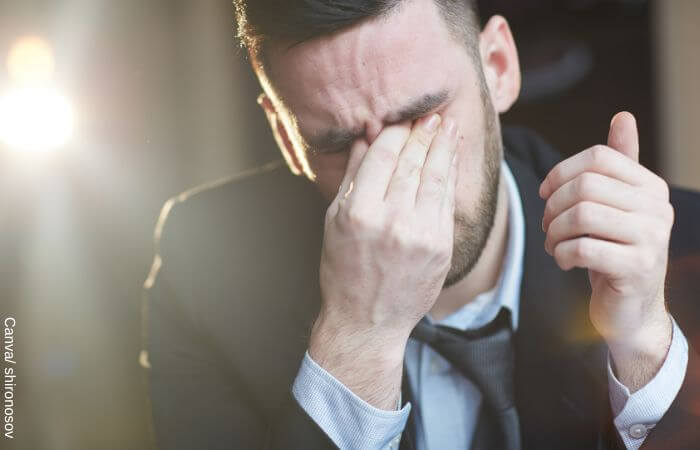 Foto de un hombre de traje llorando mientras pone una mano en sus ojos