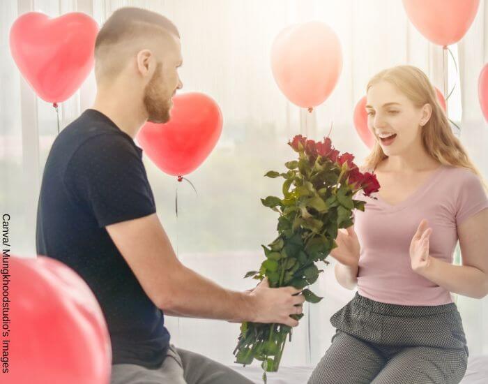 Foto de un hombre regalando flores y globos a su novia en representación de las señales que delatan a un hombre enamorado