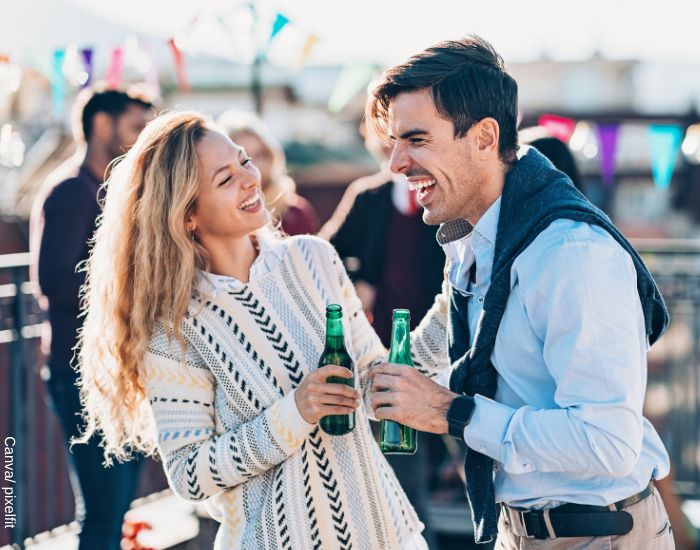 Foto de dos personas recién conocidas riéndo mientras comparten una cerveza