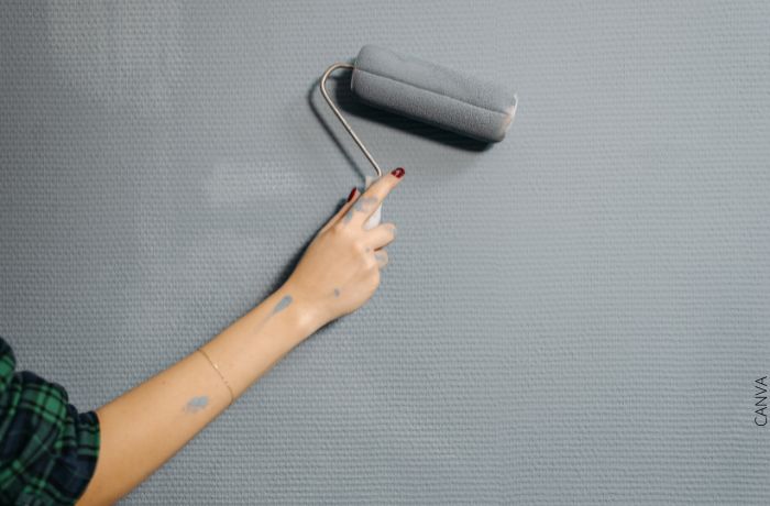 Foto de una mano pintando una pared de color gris