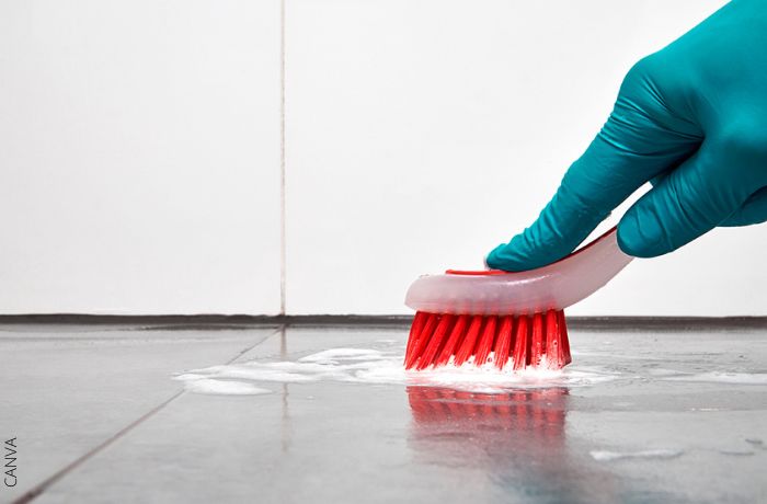 Foto de una mano limpiando el piso con un cepillo