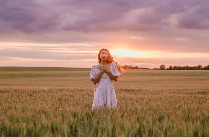 Foto de una mujer con las manos en pecho en medio del campo