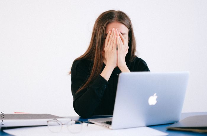 Foto de una mujer con las manos en la cara frente al computador