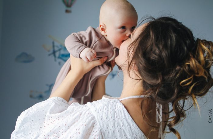 Foto de una mujer con su bebé alzado pegado a la cara