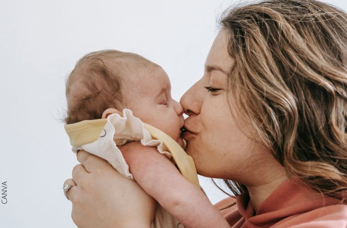 Foto de una mujer dándole un beso en la boca a su bebé