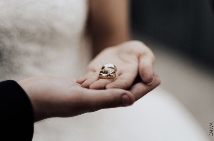 Foto de dos manos sosteniendo anillos de matrimonio