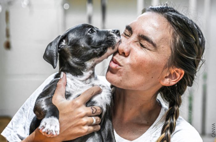 Foto de una mujer recibiendo un beso de un perro