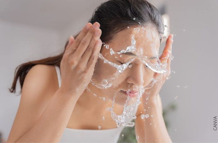 Foto de una mujer lavándose la cara con agua
