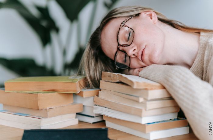 Foto de una mujer durmiendo sobre unos libros