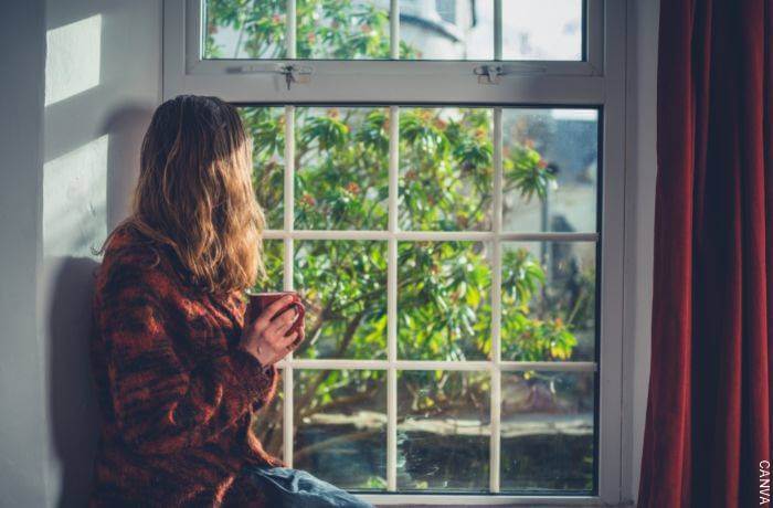 Foto de una mujer tomando té frente a una ventana