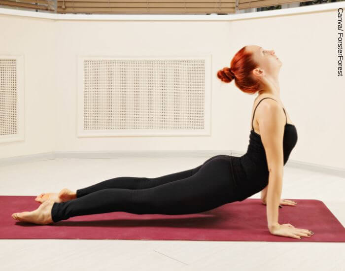 Foto de una mujer haciendo la pose cobra de yoga en representación de lo que es bueno para los cólicos menstruales