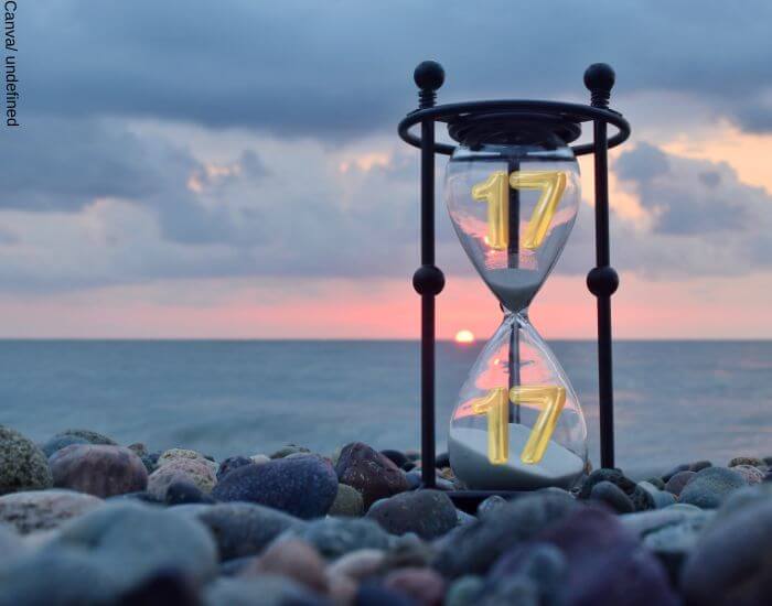 Foto de un reloj de arena en la cosa del mar sobre algunas piedras para representar la hora espejo 17 17