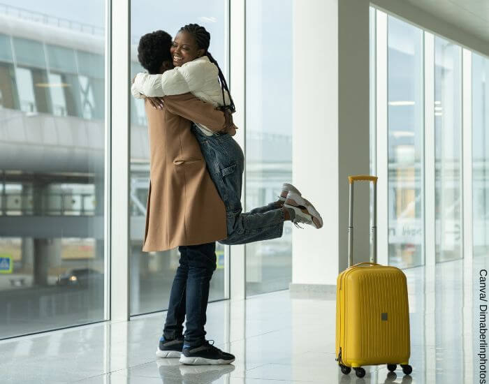 Foto de una pareja abrazada en un aeropuerto junto a una maleta