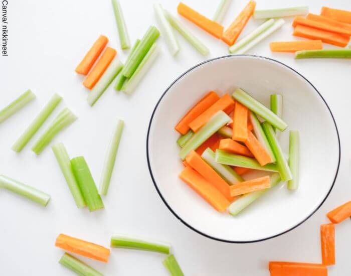 Foto de varias tajadas de zanahoria y apio, algunas dentro de un bowl y otras por fuera