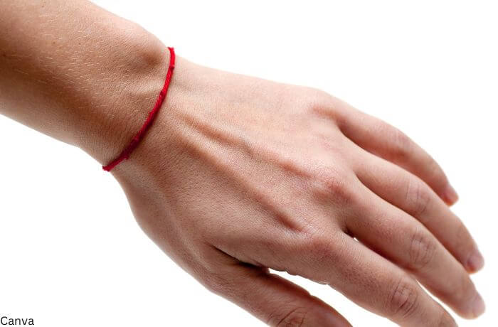 Foto de una mano con una pulsera de lana roja