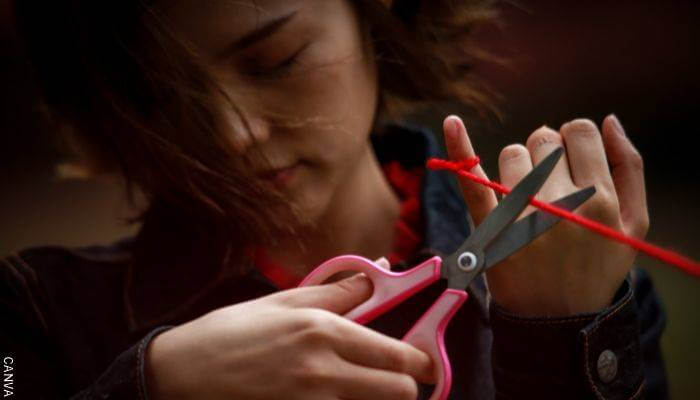 Foto de una chica cortando un hilo