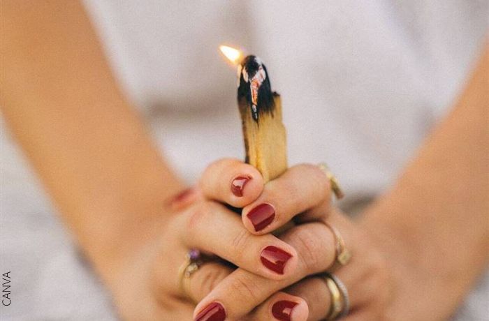 Foto de las manos de una mujer sosteniendo un palo santo encendido