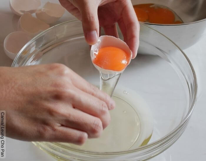 Foto de unas manos separando la clara del huevo