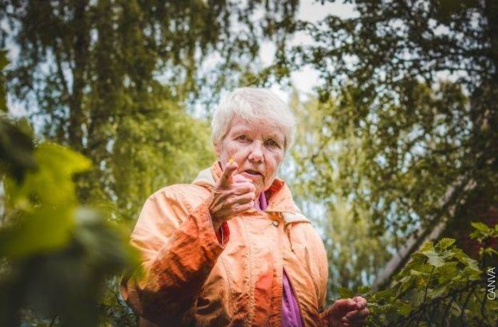 Foto de una abuela en medio del bosque señalando con el dedo