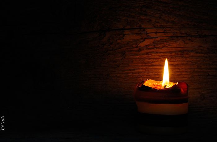 Foto de una vela encendida en medio de la oscuridad