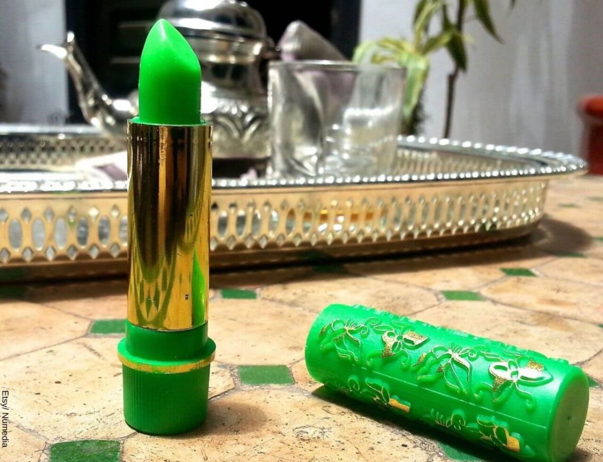Foto de un labial mágico verde sin tapa sobre una mesa