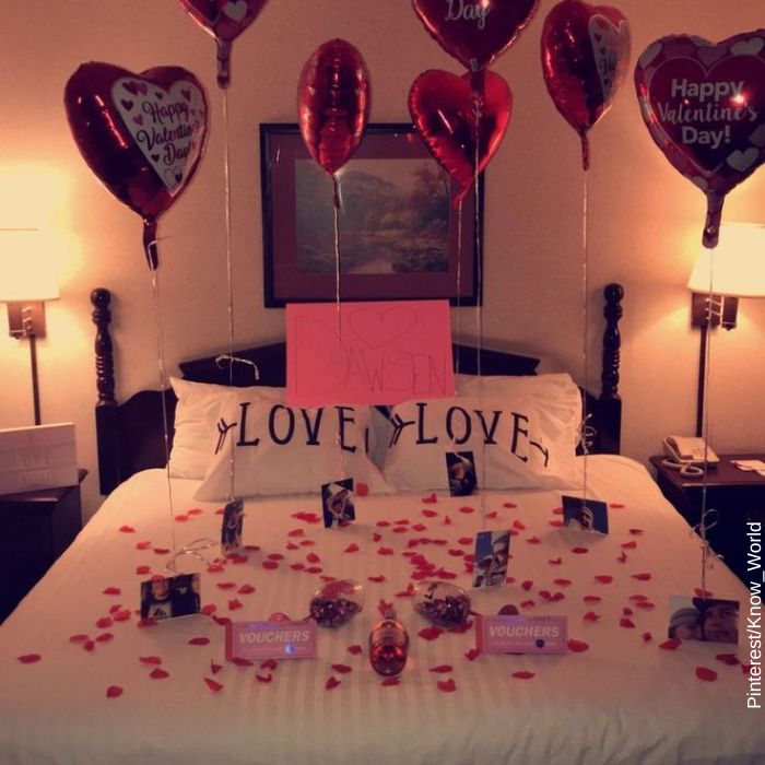 Foto d euna cama decorada con globos y palabras de amor