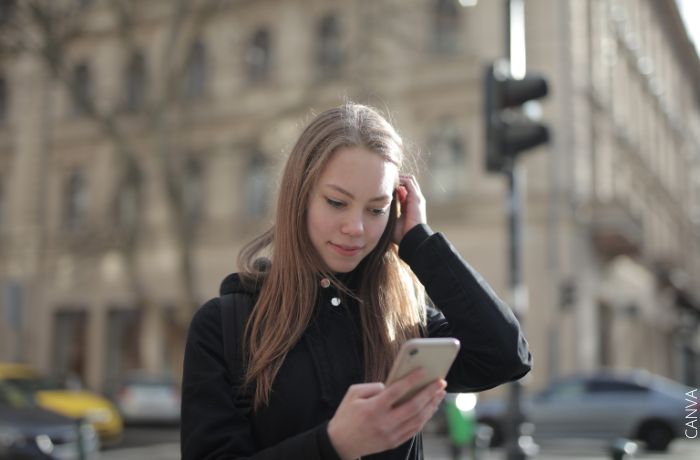 Foto de una chica mirando su telefono en la calle