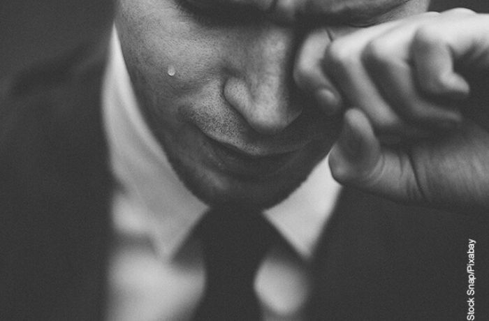 Foto a blanco y negro de un hombre llorando con una mano en un ojo