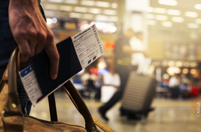 Foto de una mano con un pasaporte y un tiquete de avión