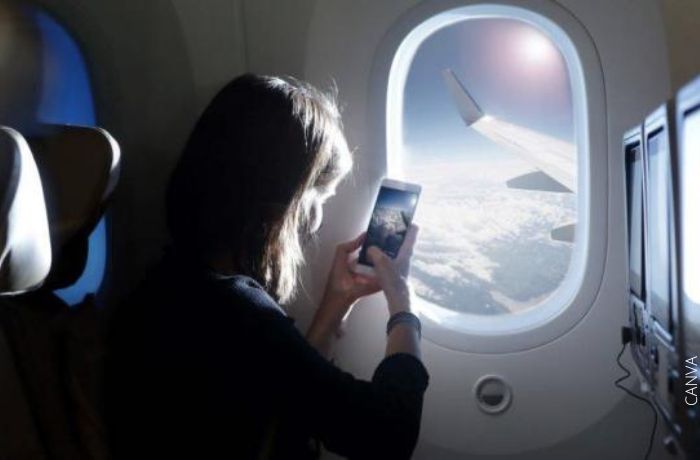 Foto de una mujer en un avión tomando una foto por la ventana