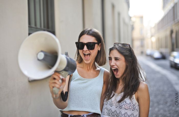 Foto de dos mujeres gritando con un megafono