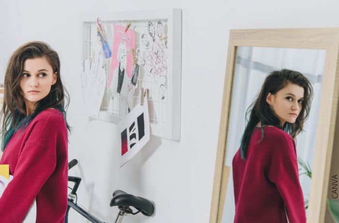 Foto de una mujer dandole la espalda al reflejo en el espejo