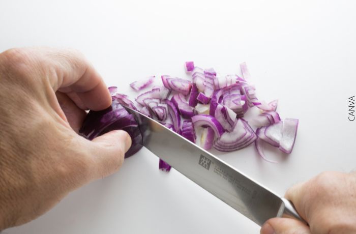 Foto de unas manos con un cuchillo picando cebolla