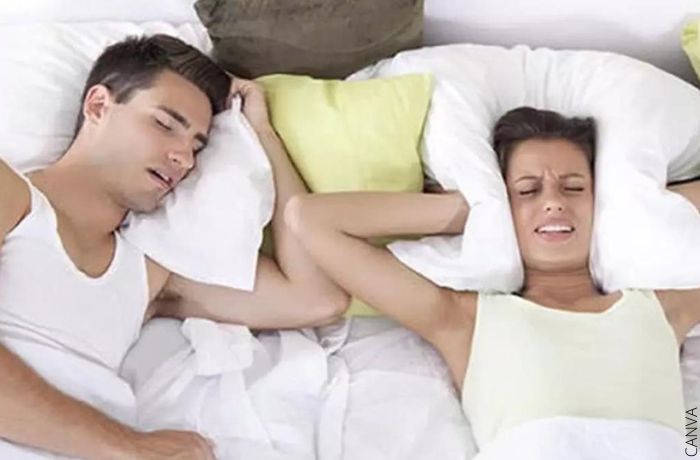 Foto de una persona tapándose los oídos de los ronquidos de un hombre para ilustrar Soñar con ver dormir a alguien, ¡estás ignorando los problemas!