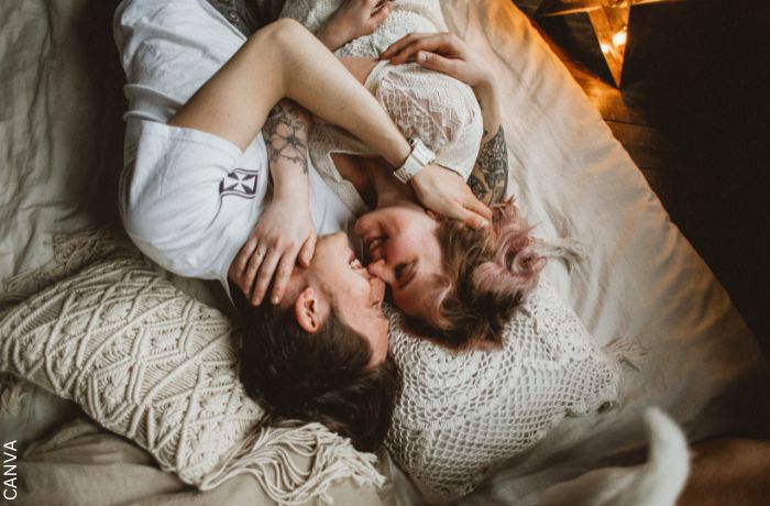 Foto de una pareja acostada en la cama sonriendo