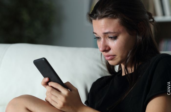 Foto de una mujer llorando mirando el celular