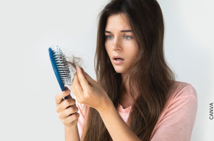 Foto de una mujer mirando el cabello que se quedó en su cepillo