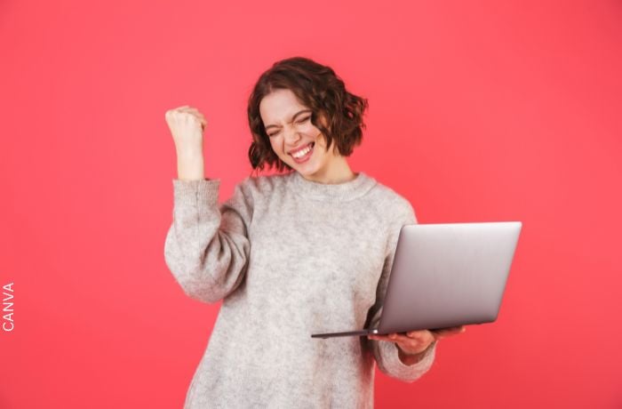 Foto de una mujer feliz con un computador en la mano