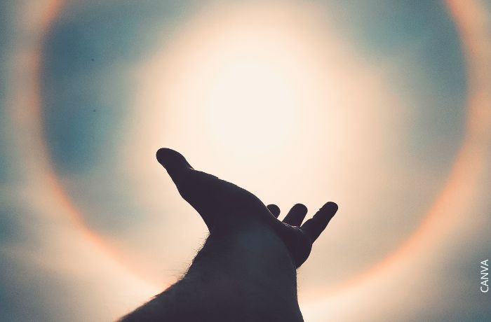 Foto de una mano apuntando a un halo solar