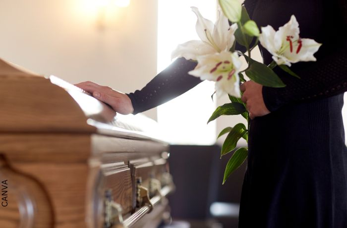 Foto de una mujer tocando un ataúd para ilustrar Mensajes de condolencias: los más adecuados para ocasión