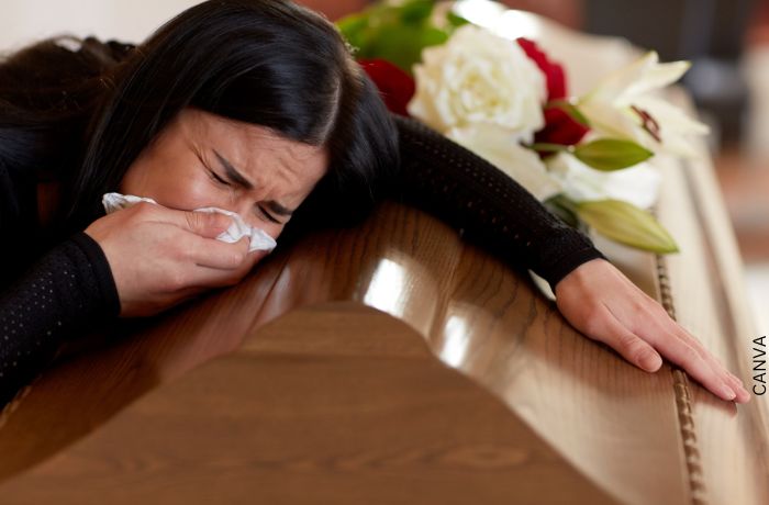Foto de una mujer sobre un ataúd para ilustrar Mensajes de condolencias: los más adecuados para ocasión