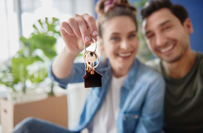 Foto de pareja con las llaves de su casa en la mano y felices