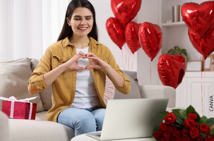 Foto de una mujer haciendo corazón con las manos al computador