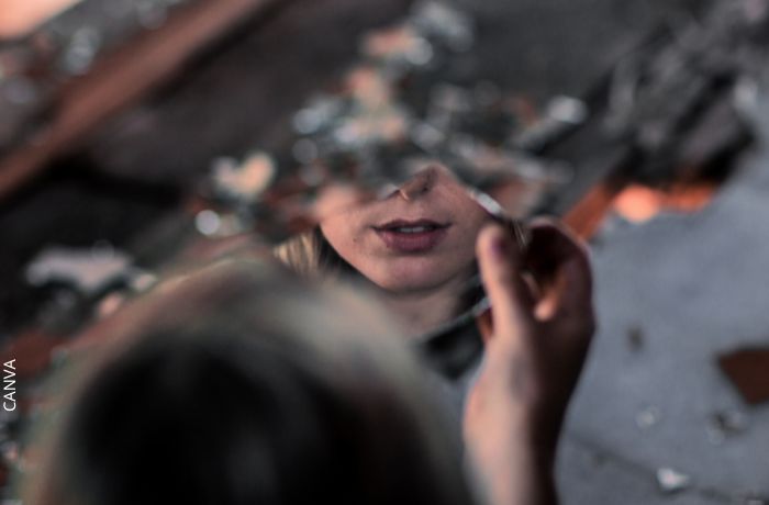 Foto de una mujer con un espejo roto en las manos