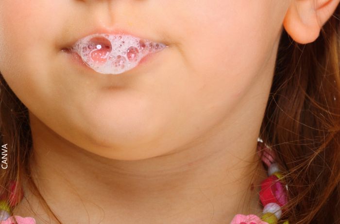 Foto de la boca de una niña dejando salir saliva